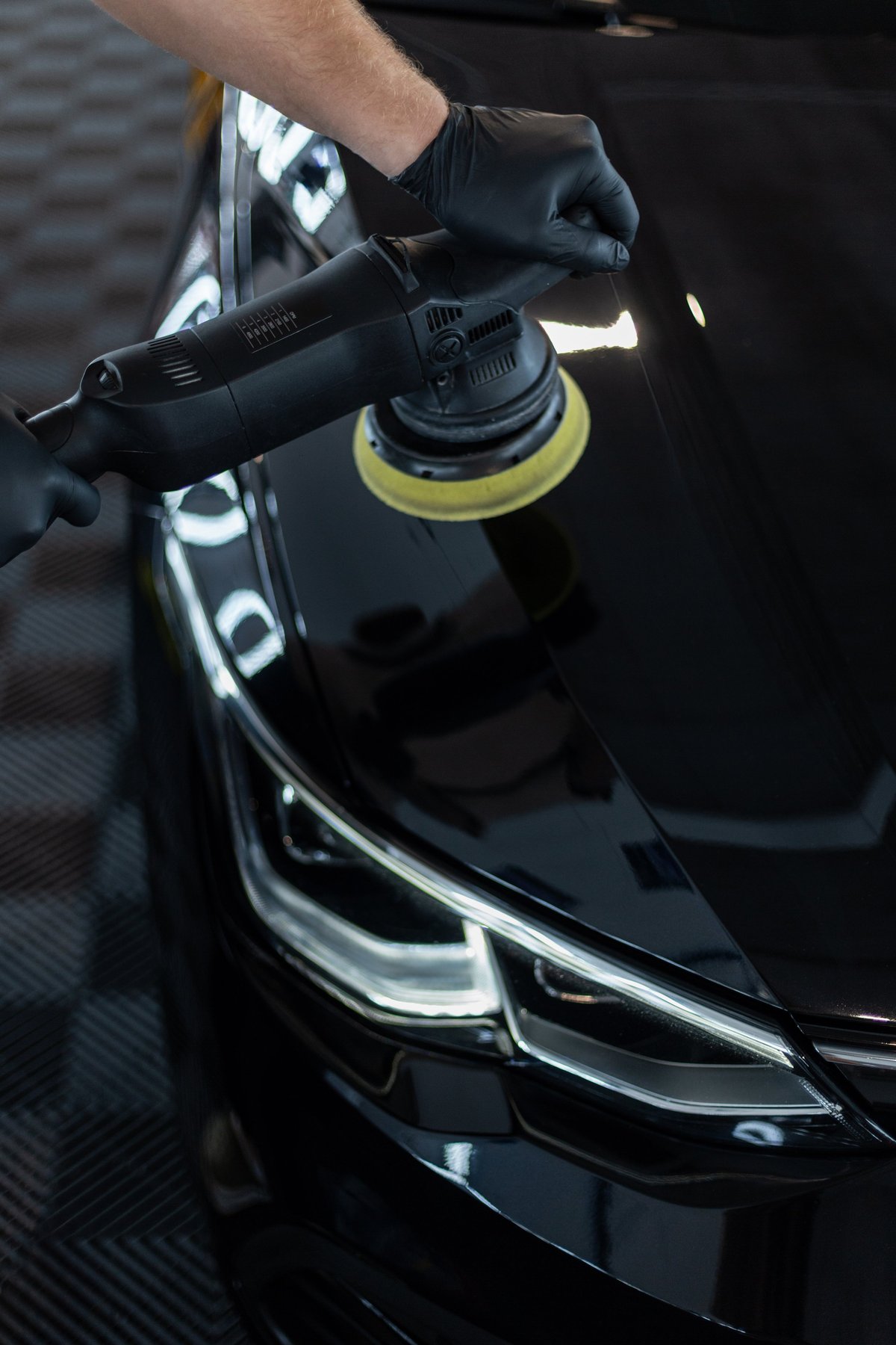 Professional detailer polishing a black car