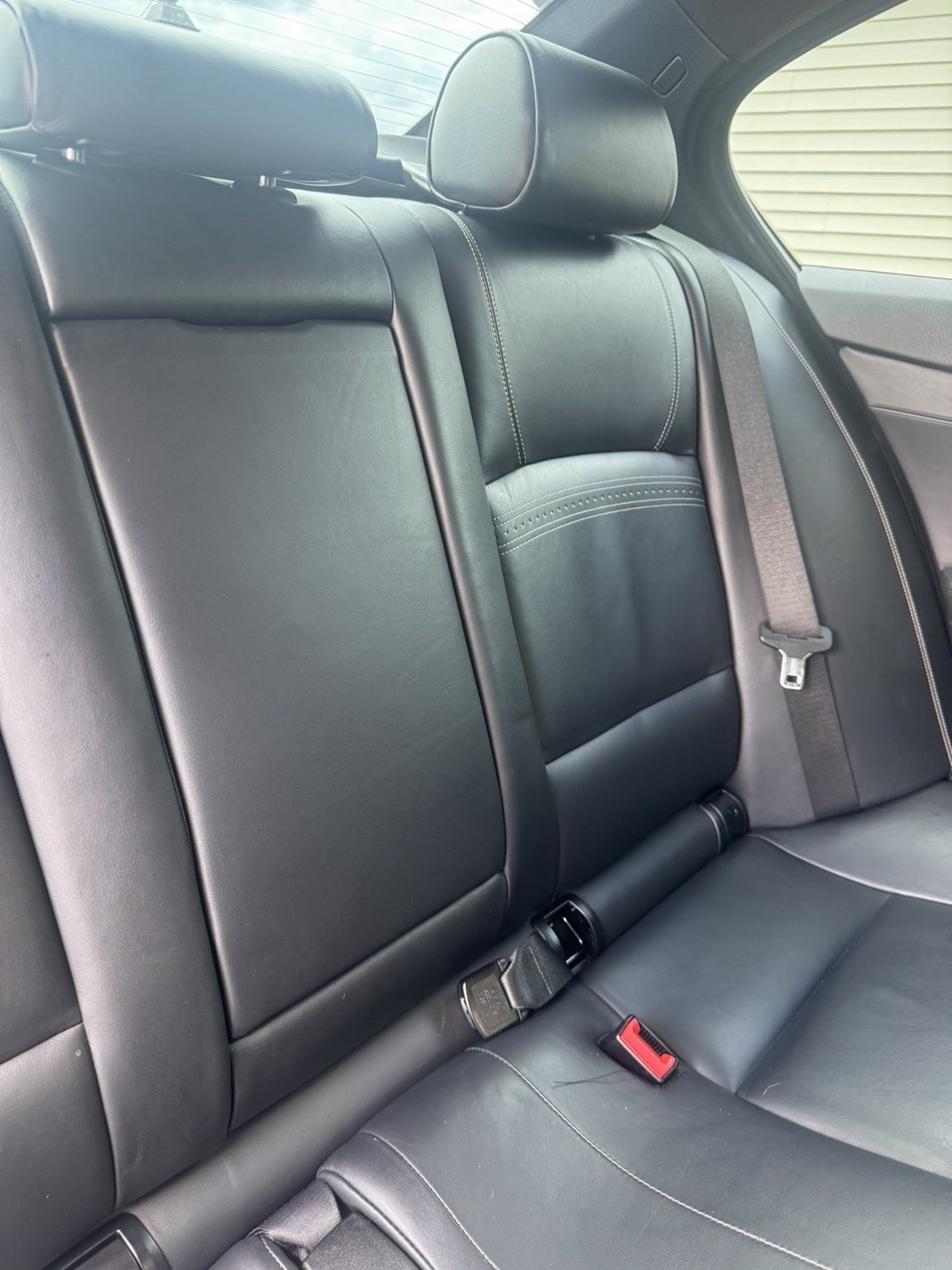 After: deep-cleaned black leather back seat with restored sheen and clean stitching